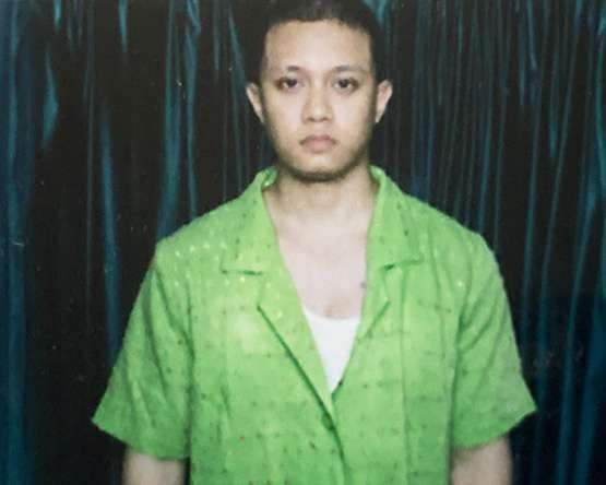 Portrait of Radito in a green shirt against a teal curtain